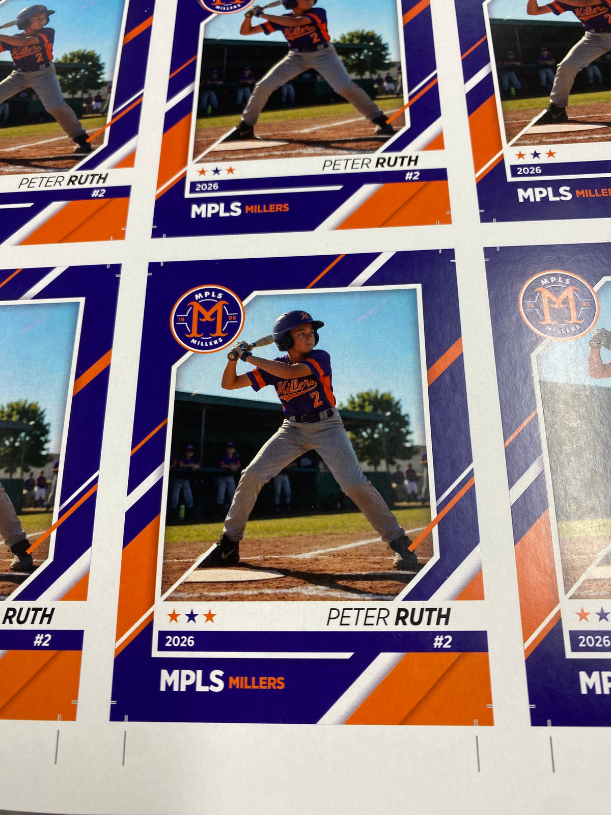 Sample sheet of personalized youth baseball cards featuring a player photo, name, number, team colors, and year